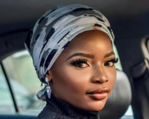 Portrait of a beautiful woman wearing a headscarf sitting inside a car, showcasing elegance and beauty.